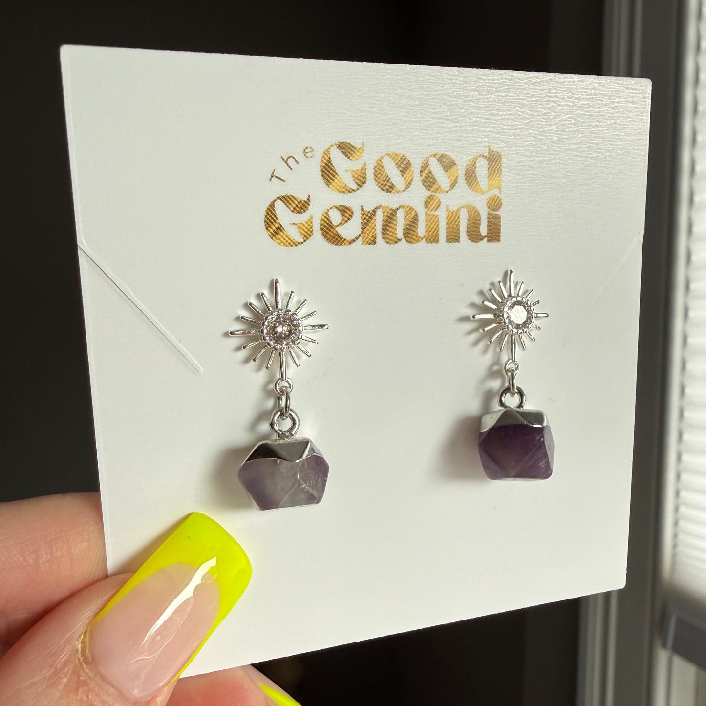 Pair of silver earrings with geometric designs on a card with 'GEMINI' text.